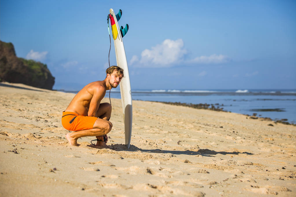jeune homme avec planche de surf sur la plage de sable près de l'océan
 - Photo, image