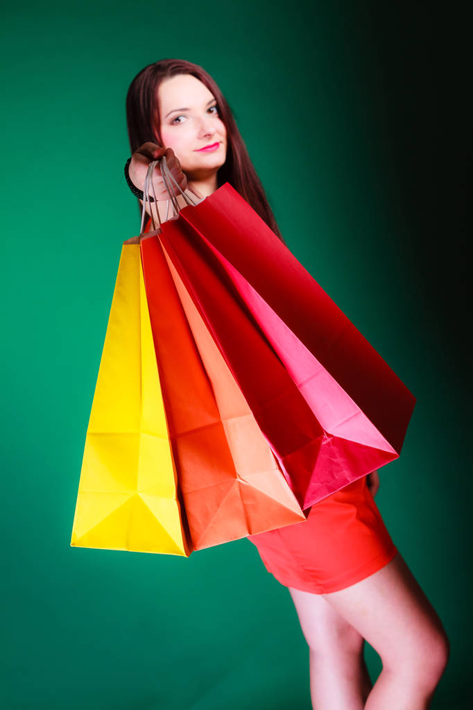 Tempo di acquisto e concetto di vendita. Giovane donna che tiene le borse in mano su sfondo verde in studio
. - Foto, immagini