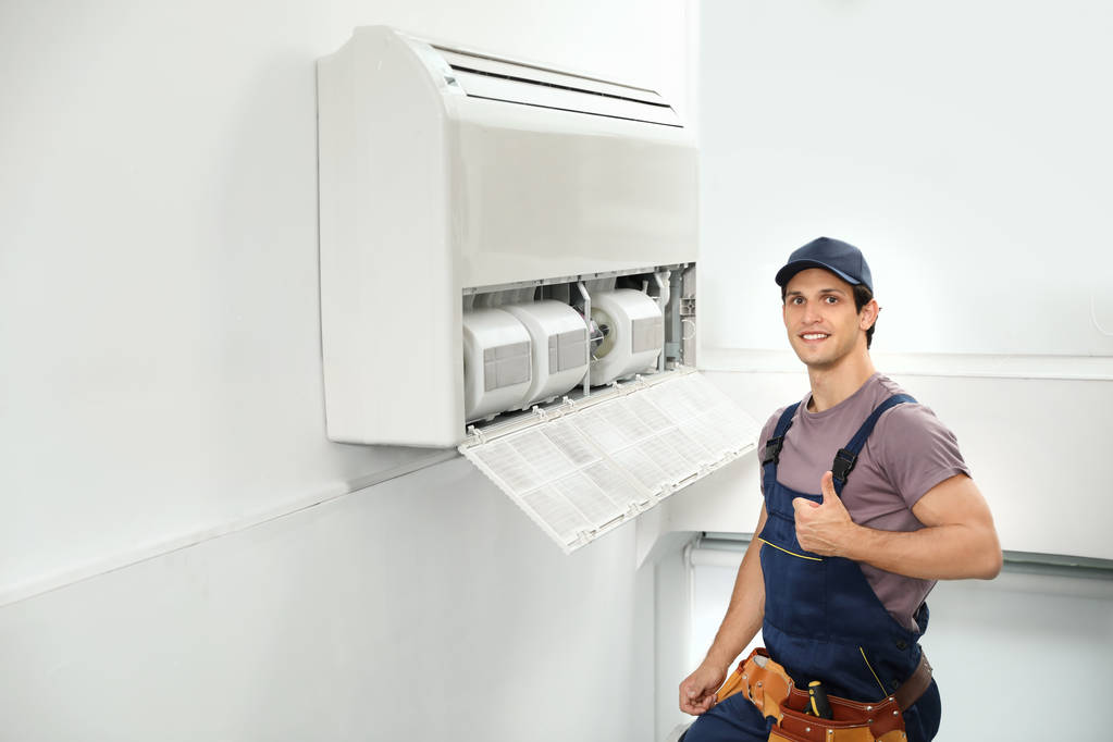 Technicien masculin debout près du climatiseur à l'intérieur
 - Photo, image