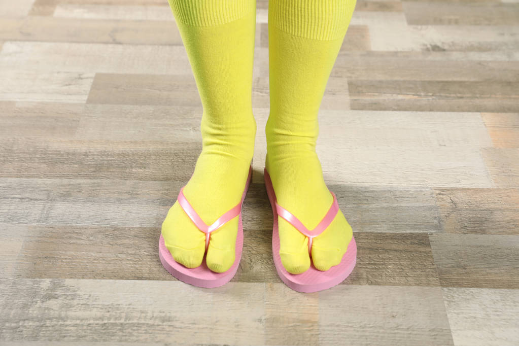 Mulher vestindo meias brilhantes com chinelos de pé no chão
 - Foto, Imagem