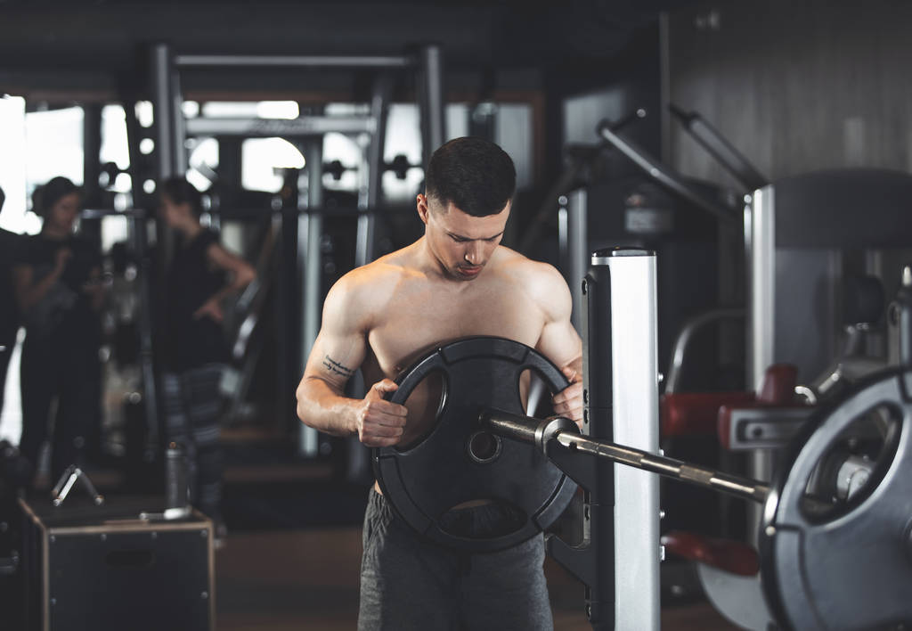 Bodybuilder trainiert mit schwerem Gerät drinnen - Foto, Bild