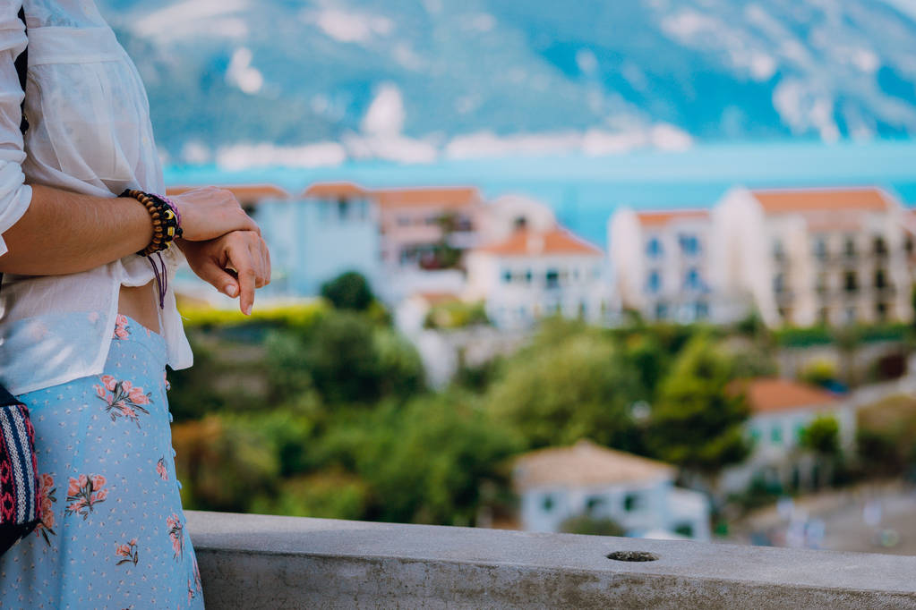 Ręce przyciąć zbliżenie. Turystyczna kobieta widokiem kolorowe spokojnej miejscowości Assos w słoneczny dzień. Kefalinia, Grecja - Zdjęcie, obraz