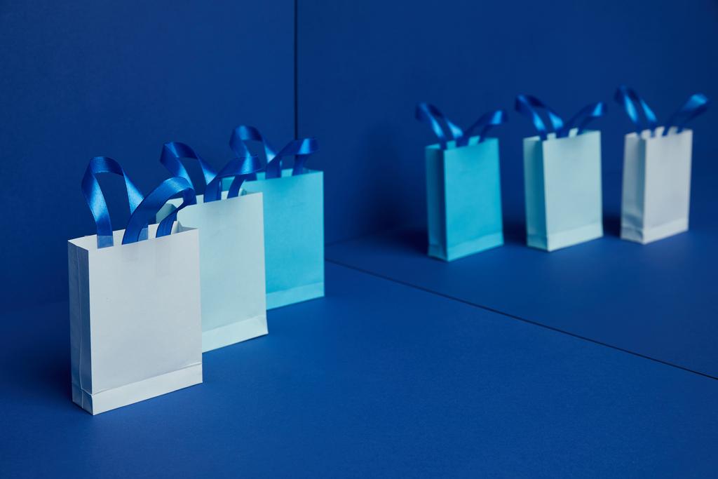 close up view of arranged paper shopping bags with mirror reflection on blue background - Photo, Image