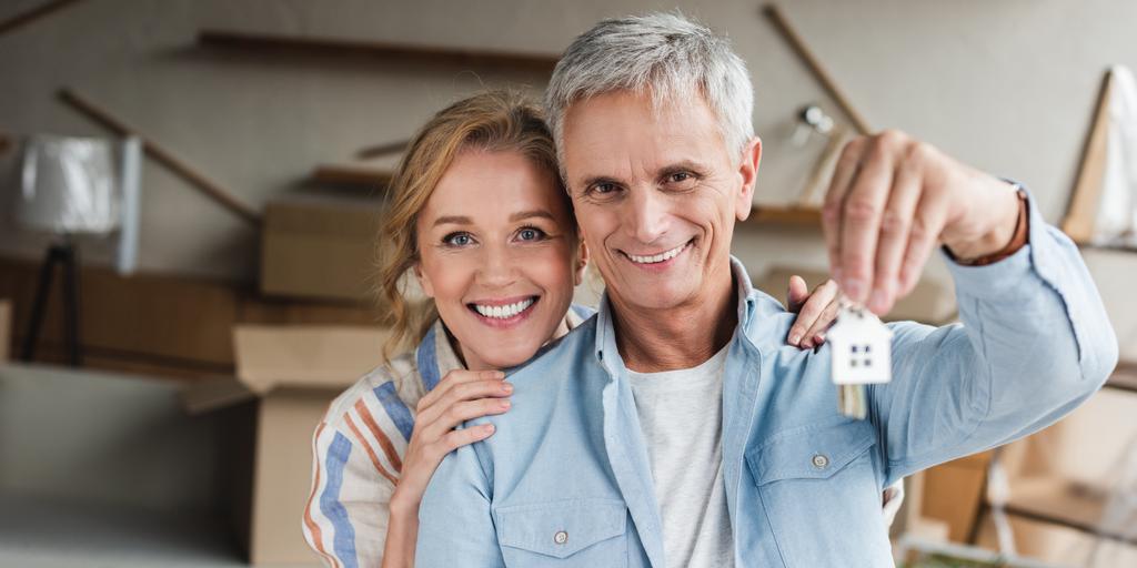 gelukkige senior paar houdt sleutels uit Nieuw appartement en lachend op camera  - Foto, afbeelding