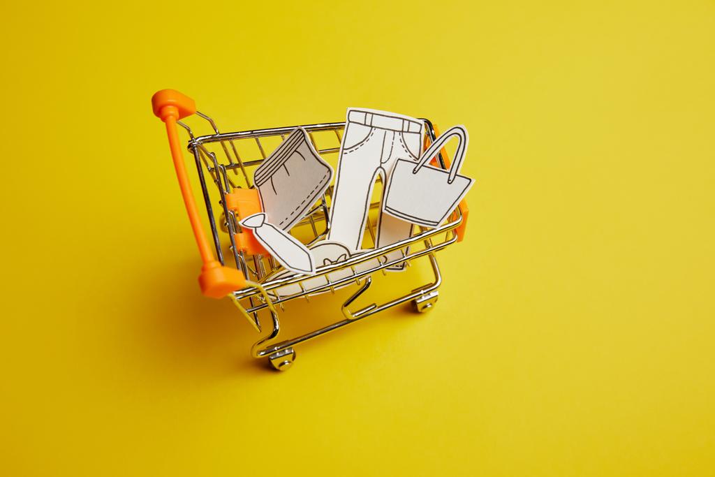 close up vista de carrinho de compras pouco com roupas feitas de papel sobre fundo amarelo
 - Foto, Imagem
