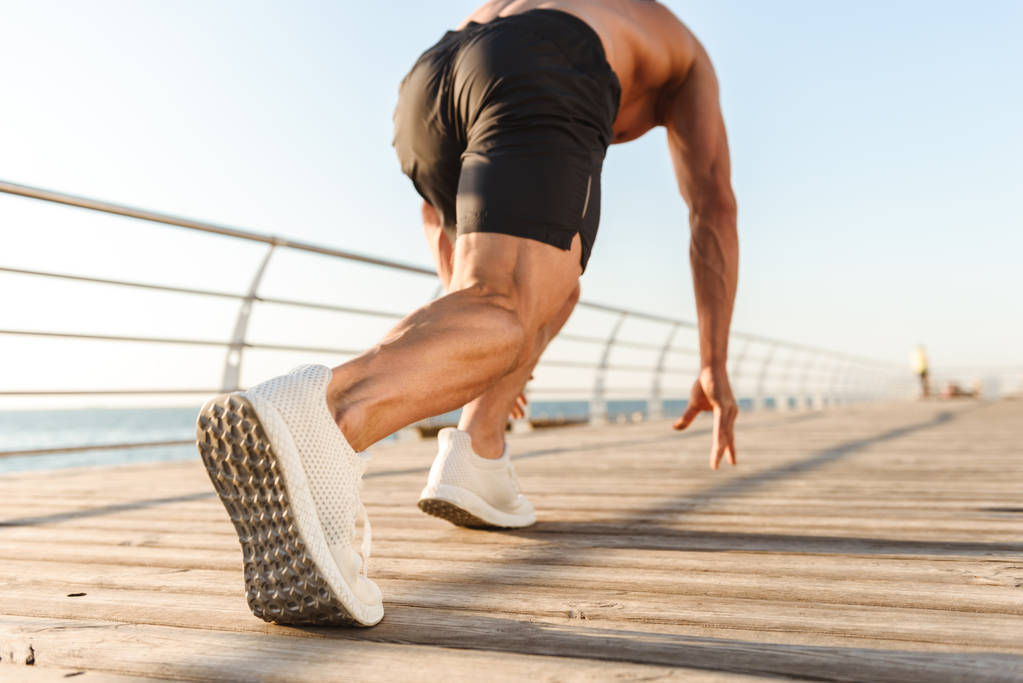 Takaisin näkymä lihaksikas nuori paidaton urheilija saada valmis juosta meren rannalla
 - Valokuva, kuva