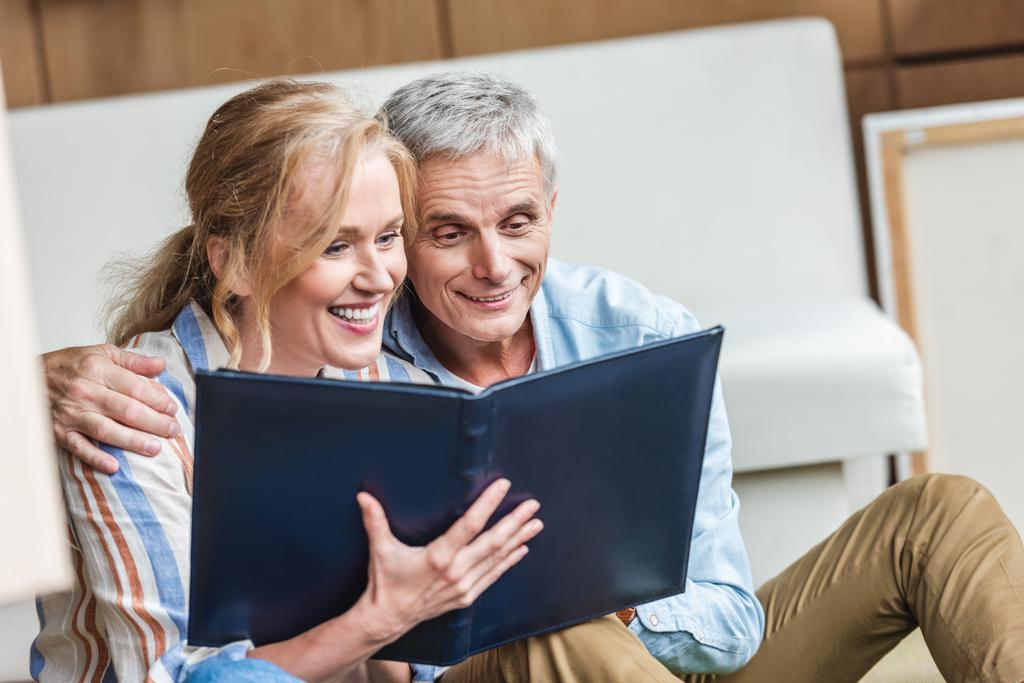beautiful happy elderly couple looking at photo album together - Photo, Image