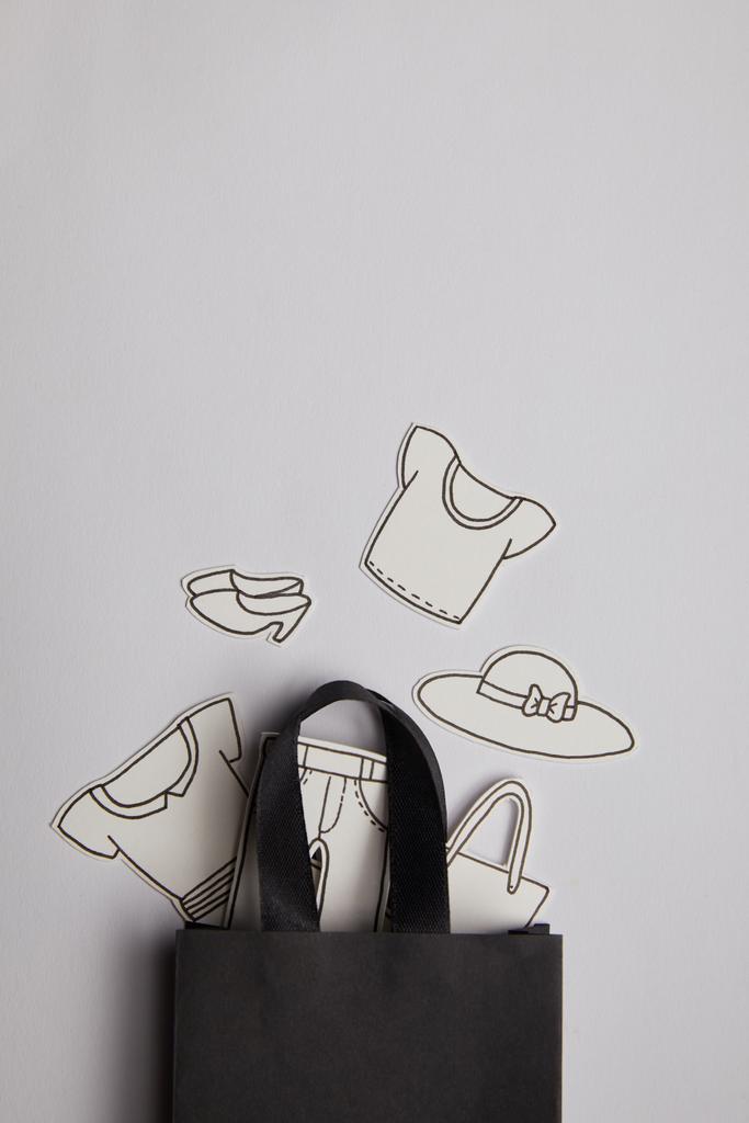Konsept alışveriş gri arka plan üzerinde siyah alışveriş çantası ve kağıt giyim üstten görünüm - Fotoğraf, Görsel