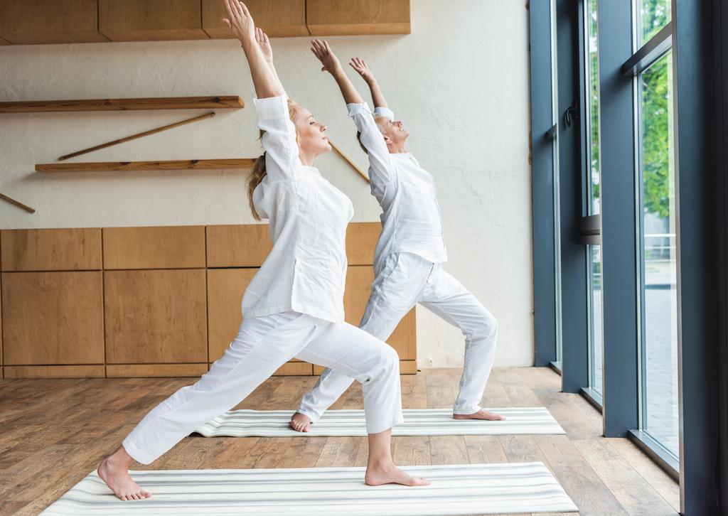 Босоногая спортивная старшая пара практикующая йогу дома
 - Фото, изображение