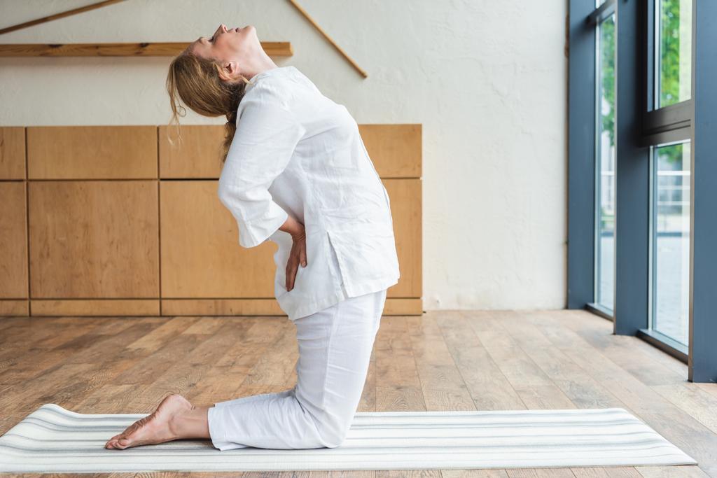vista lateral de mujer madura deportiva practicando yoga en estera de yoga
 - Foto, imagen