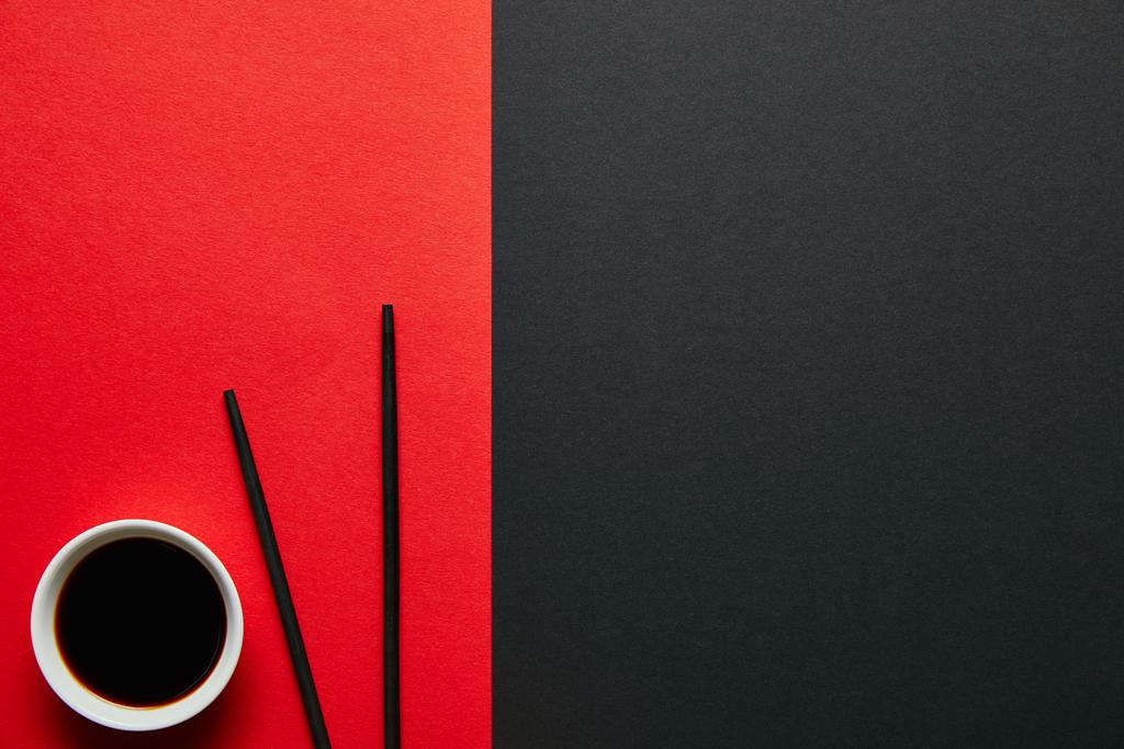 赤と黒の背景の上に茶碗やお箸醤油のトップ ビュー  - 写真・画像