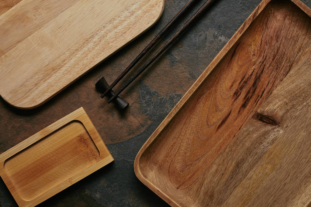 плоска лежала з порожніми дерев'яними тарілками і паличками для суші на темній стільниці
 - Фото, зображення