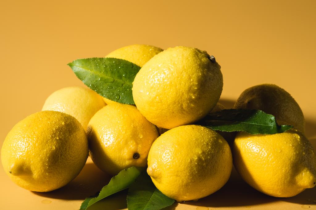 fresh wet lemons with leaves on yellow background - Photo, Image