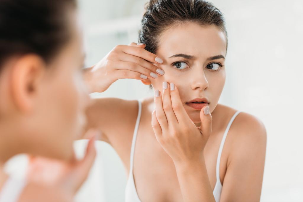 foyer sélectif de fille vérifier la peau du visage et de regarder miroir dans la salle de bain
   - Photo, image