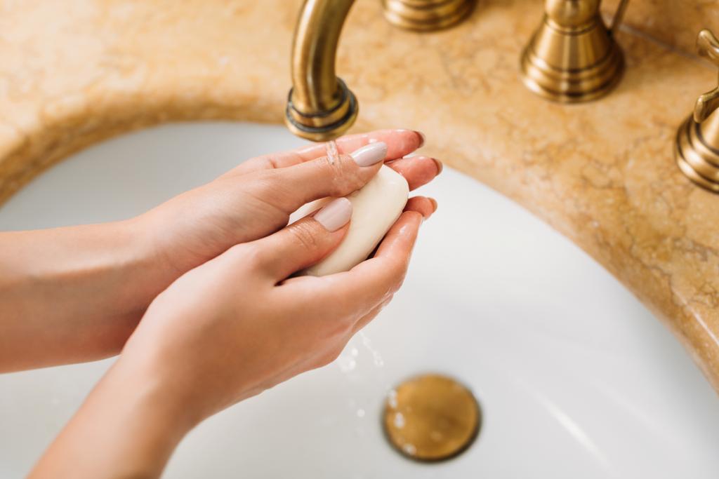 rajattu kuva naisen pestä kädet saippualla kylpyhuoneessa
 - Valokuva, kuva