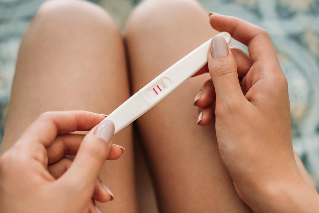 妊娠テストを保持している若い女性のショットをトリミング - 写真・画像