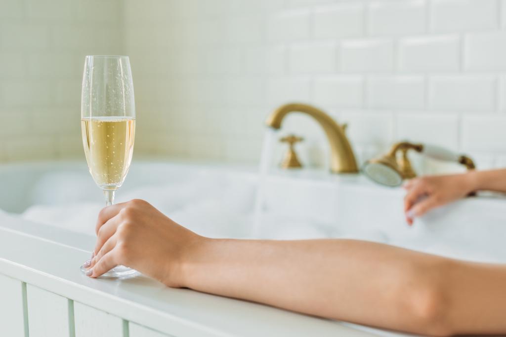 обрезанный снимок молодой женщины с бокалом шампанского в ванной
 - Фото, изображение