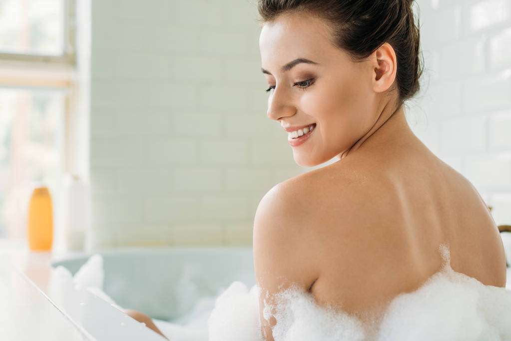 hermosa sonrisa chica desnuda sentada en la bañera con espuma
 - Foto, Imagen
