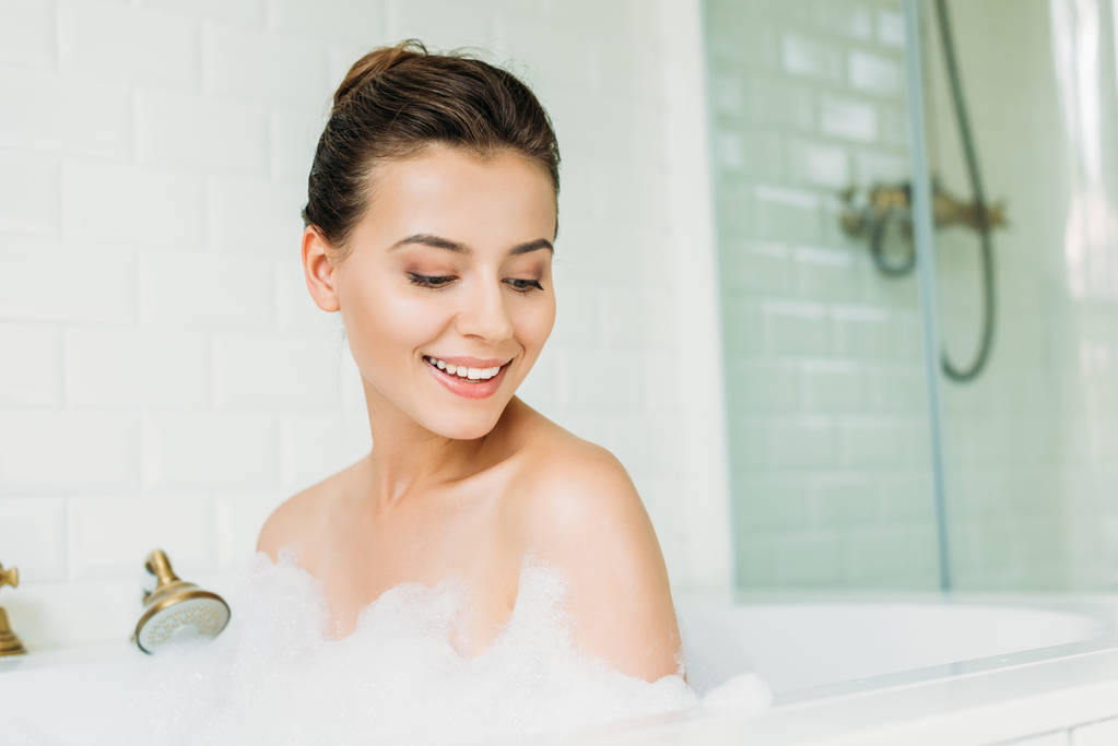 bella giovane donna sorridente guardando la schiuma nella vasca da bagno
  - Foto, immagini
