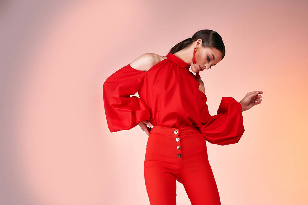 かなり美しいセクシーなエレガンス女性ファッションモデルグラマーポーズは赤い色のズボンシルクブラウス服のためのパーティー夏コレクションメイクヘアスタイルブルネット成功アクセサリーバッグジュエリースタジオ. - 写真・画像