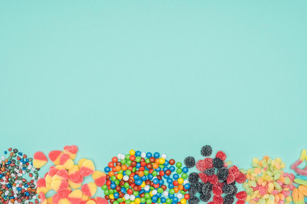 vista superior de diferentes dulces de colores aislados en turquesa
 - Foto, Imagen