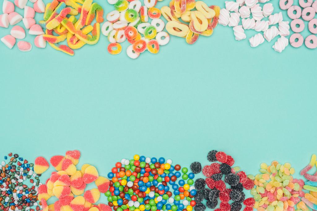 vista superior de caramelos de gelatina, malvaviscos y dragee aislados en turquesa
 - Foto, imagen