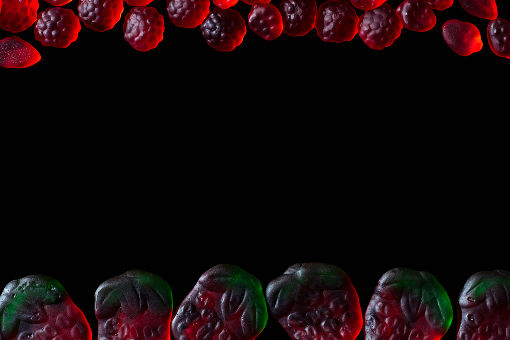 top view of jelly candies in shape of raspberries and strawberries isolated on black - Photo, Image