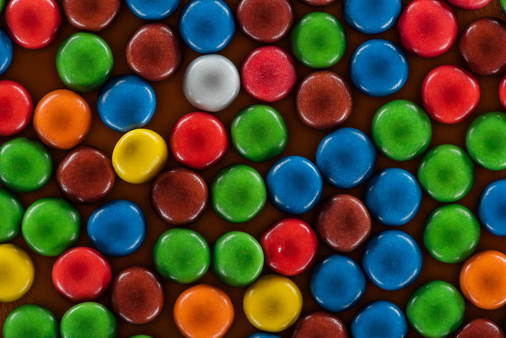 вид сверху на вкусные яркие драже конфеты на коричневой поверхности
  - Фото, изображение