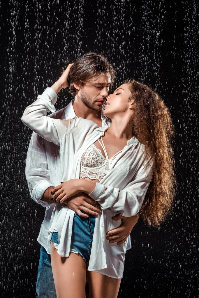 retrato de pareja seductora abrazándose bajo la lluvia aislada sobre negro
 - Foto, Imagen