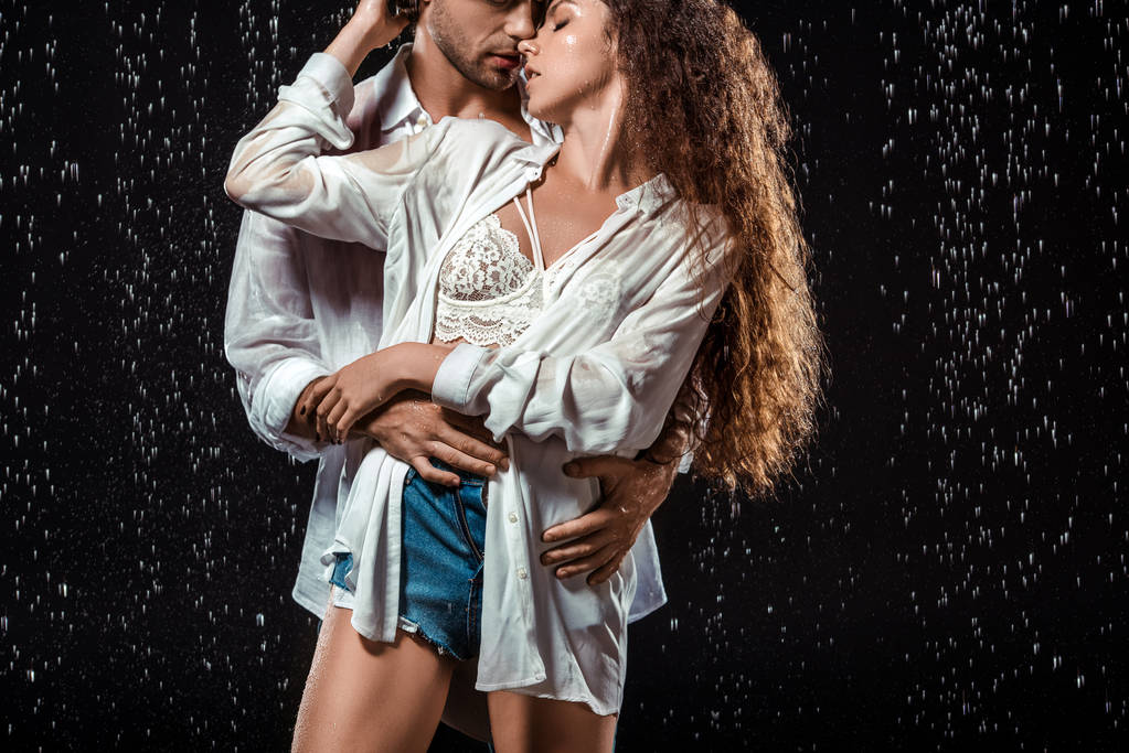 portret uwodzicielski para przytulanie pod deszcz na czarnym tle - Zdjęcie, obraz