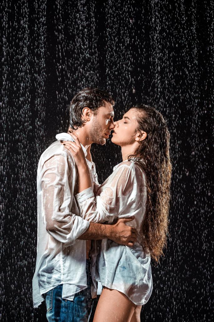 Μερική άποψη του ζευγάρι φιλί κάτω από την βροχή που απομονώνονται σε μαύρο - Φωτογραφία, εικόνα