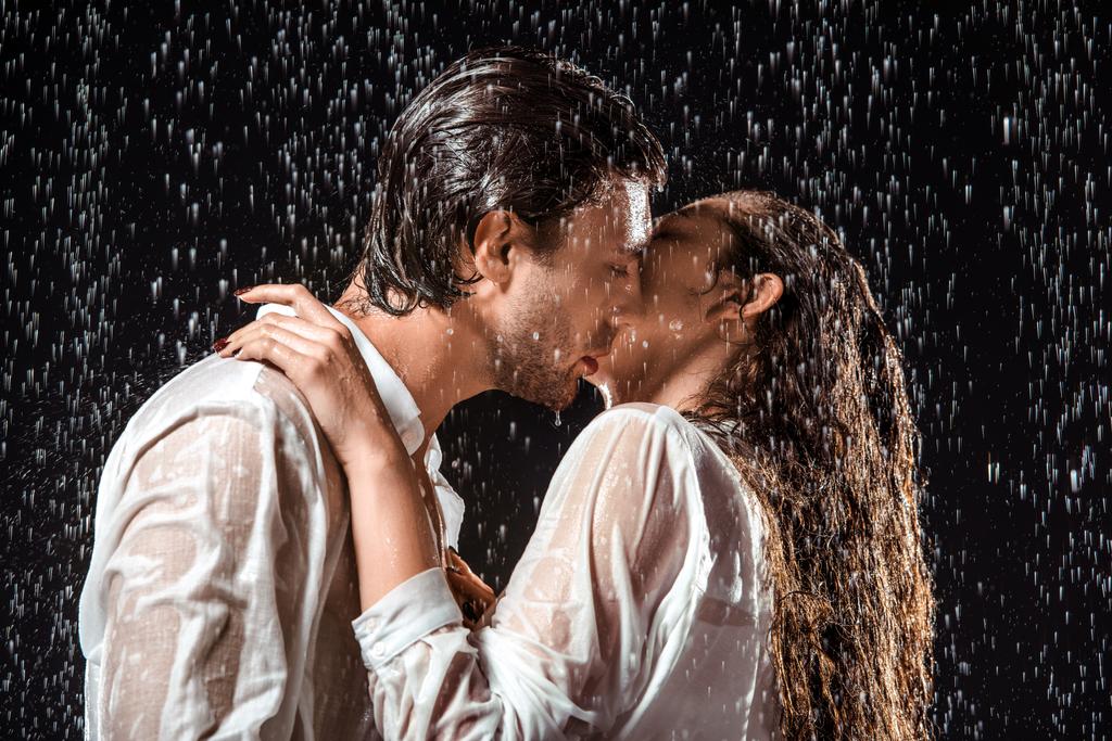 siyah izole yağmur altında çift öpüşme yan görünüm - Fotoğraf, Görsel