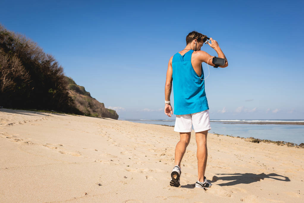 вид сзади спортсмен гуляющий по берегу моря, Бали, Индонезия
 - Фото, изображение