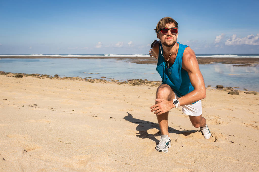 Αθλητικός τύπος κάνοντας lunges κατά τη διάρκεια της προπόνηση στην παραλία κοντά στη θάλασσα - Φωτογραφία, εικόνα