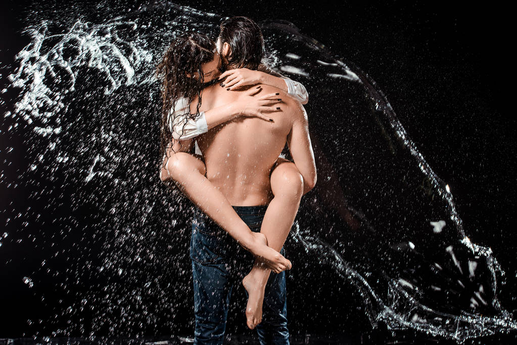 back view of sexy young couple swilled with water isolated on black - Photo, Image