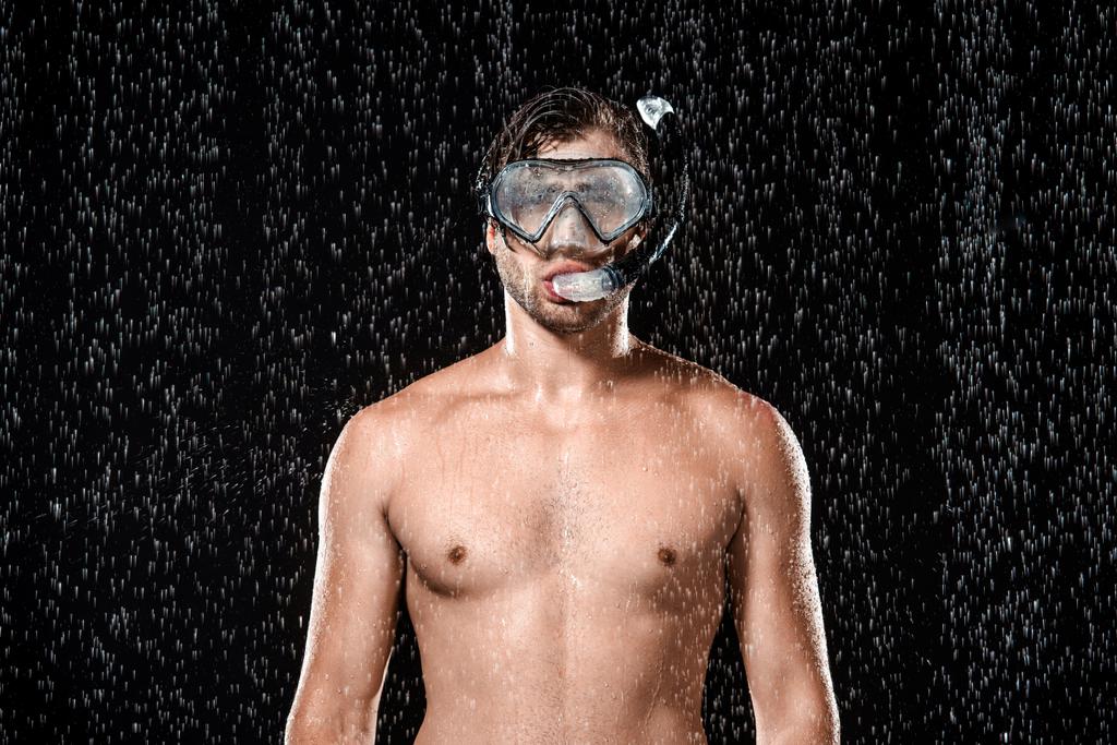 portrait of shirtless man in swimming mask with snorkel standing under water drops isolated on black - Photo, Image