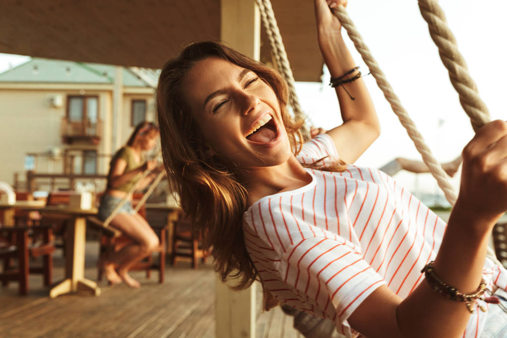 Фото счастливой юной леди на открытом воздухе на пляже, катающейся на качелях
. - Фото, изображение