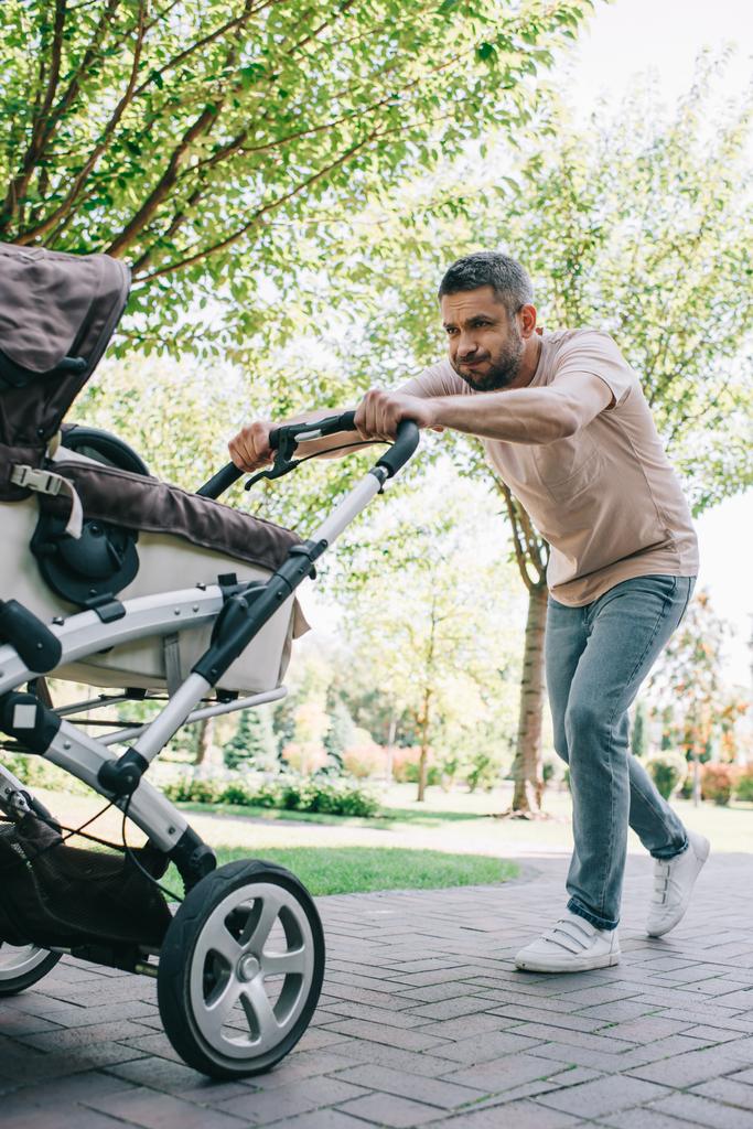 πατέρα, το περπάτημα με βαριά baby μεταφορά στο πάρκο - Φωτογραφία, εικόνα