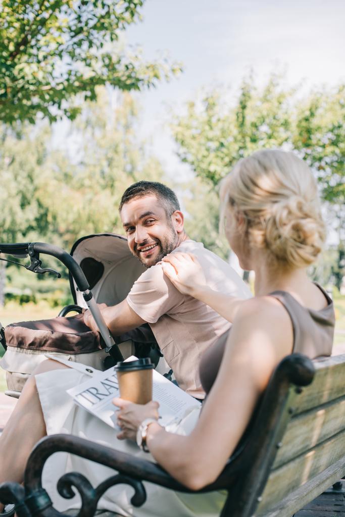 moglie seduta vicino alla carrozzina con il caffè per andare a viaggiare giornale e guardando il marito
 - Foto, immagini