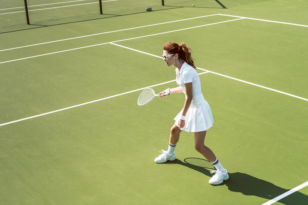 joven jugadora de tenis en gafas de sol jugando tenis en la cancha
 - Foto, imagen