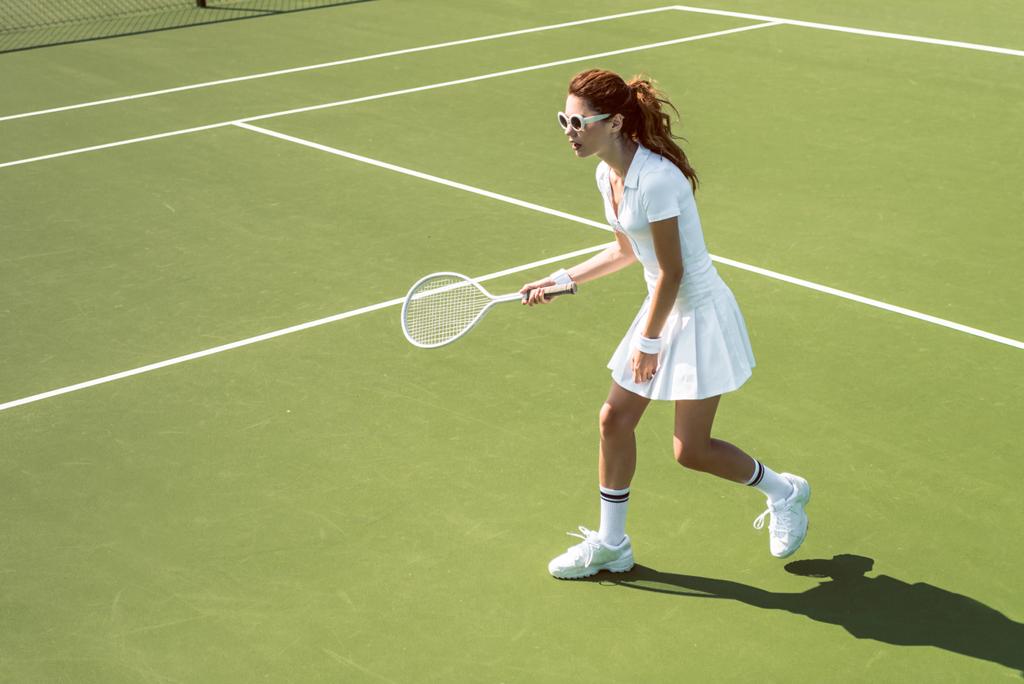 joven jugadora de tenis en gafas de sol jugando tenis en la cancha
 - Foto, imagen