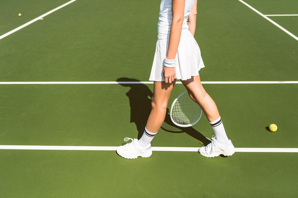 částečný pohled tenistka v bílém oblečení s raketou na tenisový kurt - Fotografie, Obrázek