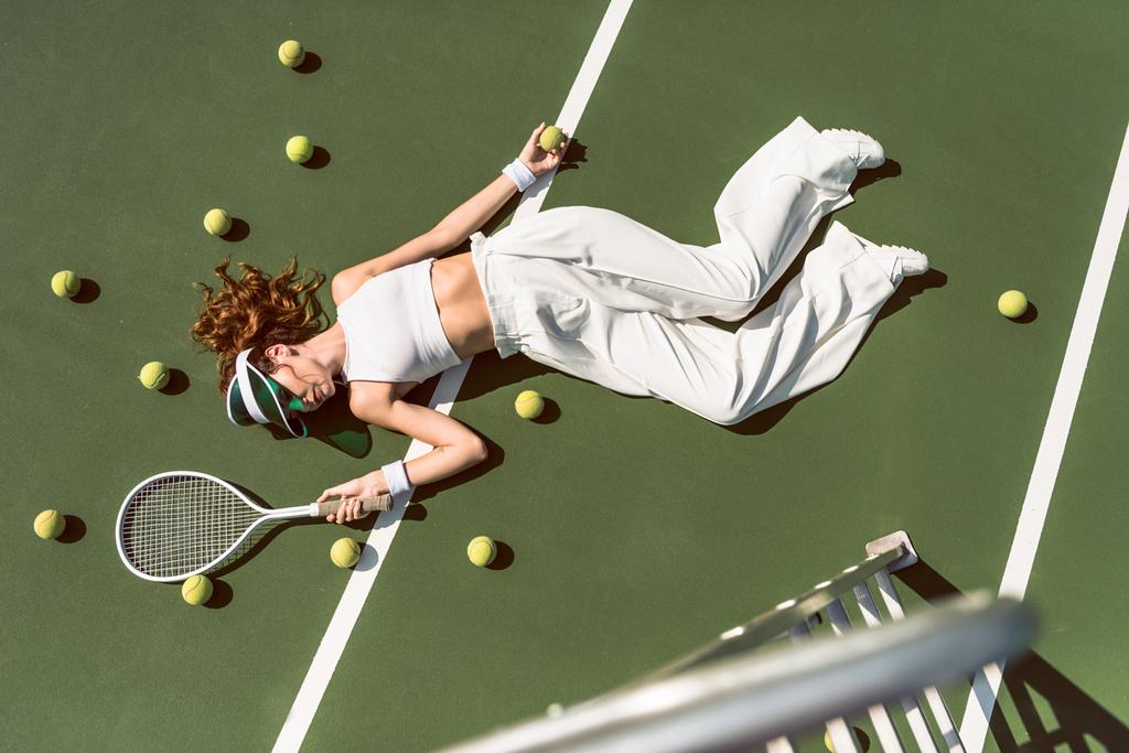 atrakcyjna kobieta w białych ubrań i WPR leży z rakiety, leżącego na kort tenisowy z rakiety, ogólny widok - Zdjęcie, obraz