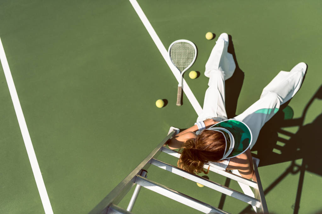 vista aérea de la mujer en ropa blanca con estilo y la tapa posando en silla de árbitro en la cancha de tenis
 - Foto, Imagen