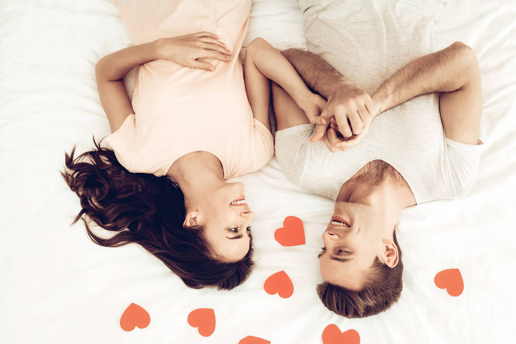 La pareja feliz está acostada en la cama en San Valentín. Amaos. Sweetheart 's Holiday Concept. Origami Rosas. Celebrando la fecha. Joven y guapo. Ojos cerrados Pareja. Felices juntos
. - Foto, imagen