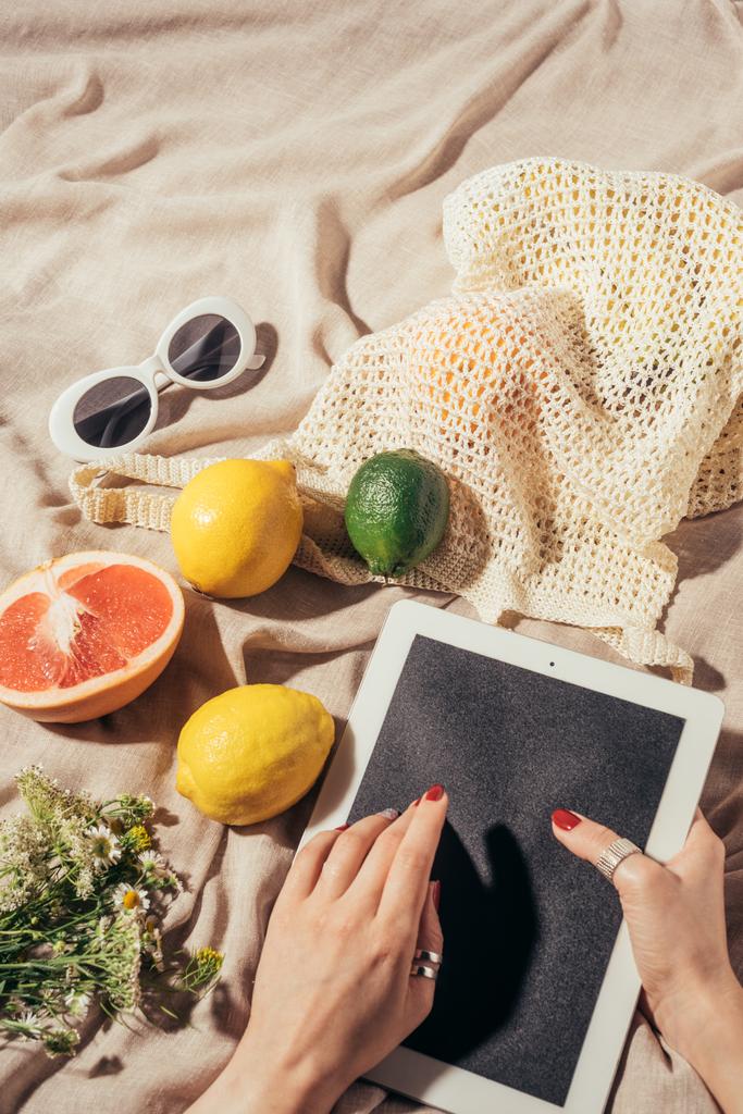 taze meyve ve güneş gözlüğü ile dijital tablet ve dize çanta kullanan kişi resmini kırpılmış - Fotoğraf, Görsel