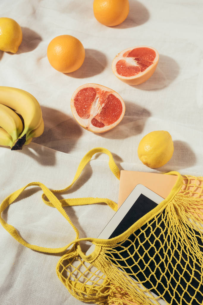 digitale Tablette im gelben Saitensack und frischen reifen tropischen Früchten   - Foto, Bild