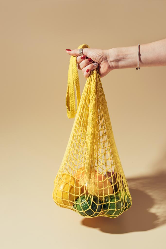 osittainen näkymä henkilö tilalla merkkijono laukku tuoreita trooppisia hedelmiä ruskea
    - Valokuva, kuva
