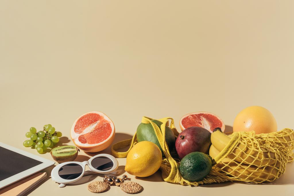Okulary, kolczyki, cyfrowego tabletu i dojrzałych owoców w ciągu torba na brązowy   - Zdjęcie, obraz