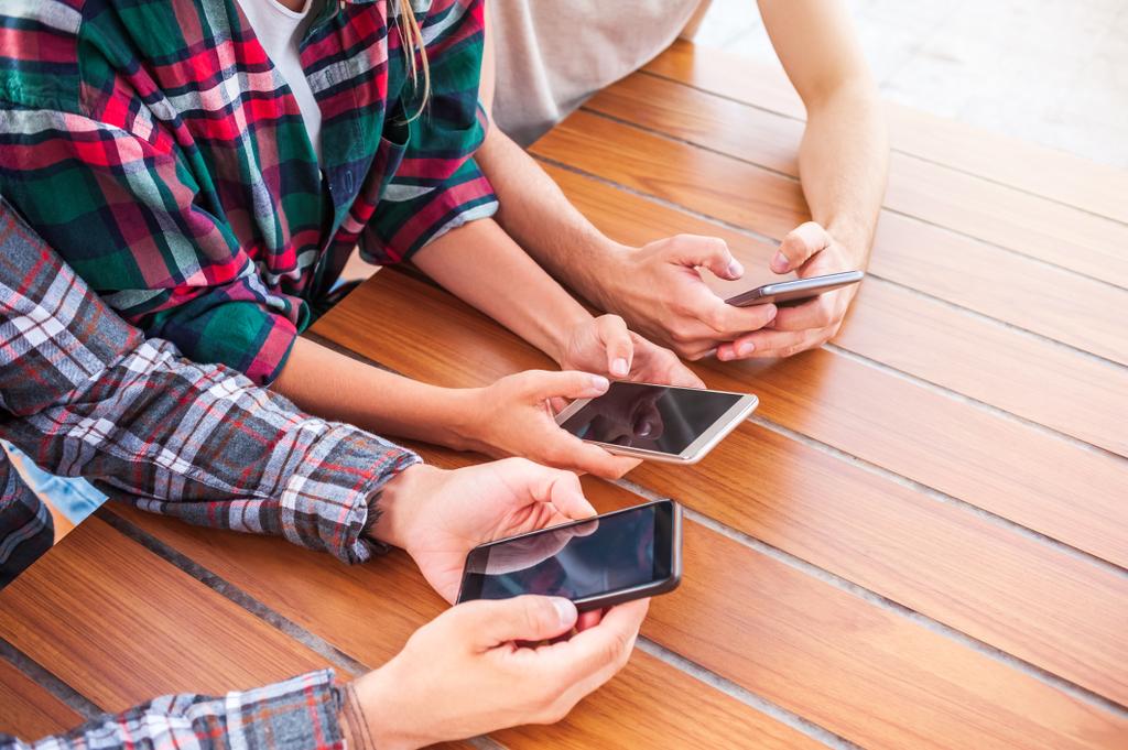обрізаний знімок молодих друзів за допомогою смартфонів з порожніми екранами
 - Фото, зображення